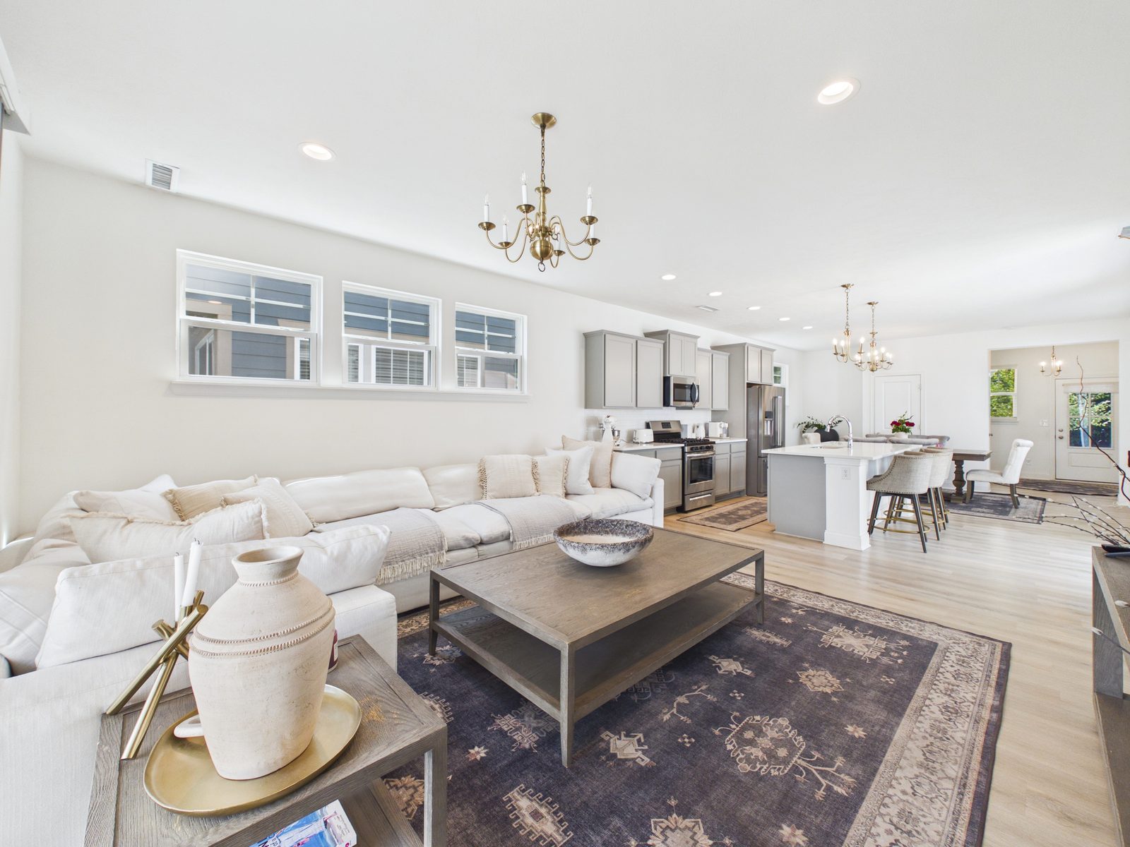 Bright living room with a sectional, chandelier, and windows